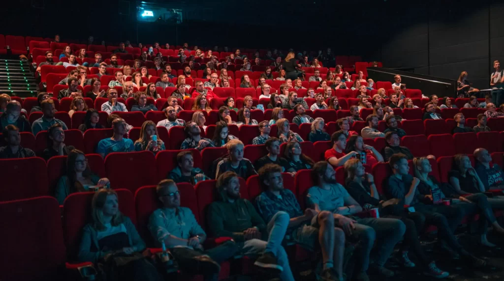 salle de cinéma remplie de spectateurs assis sur des sièges rouges