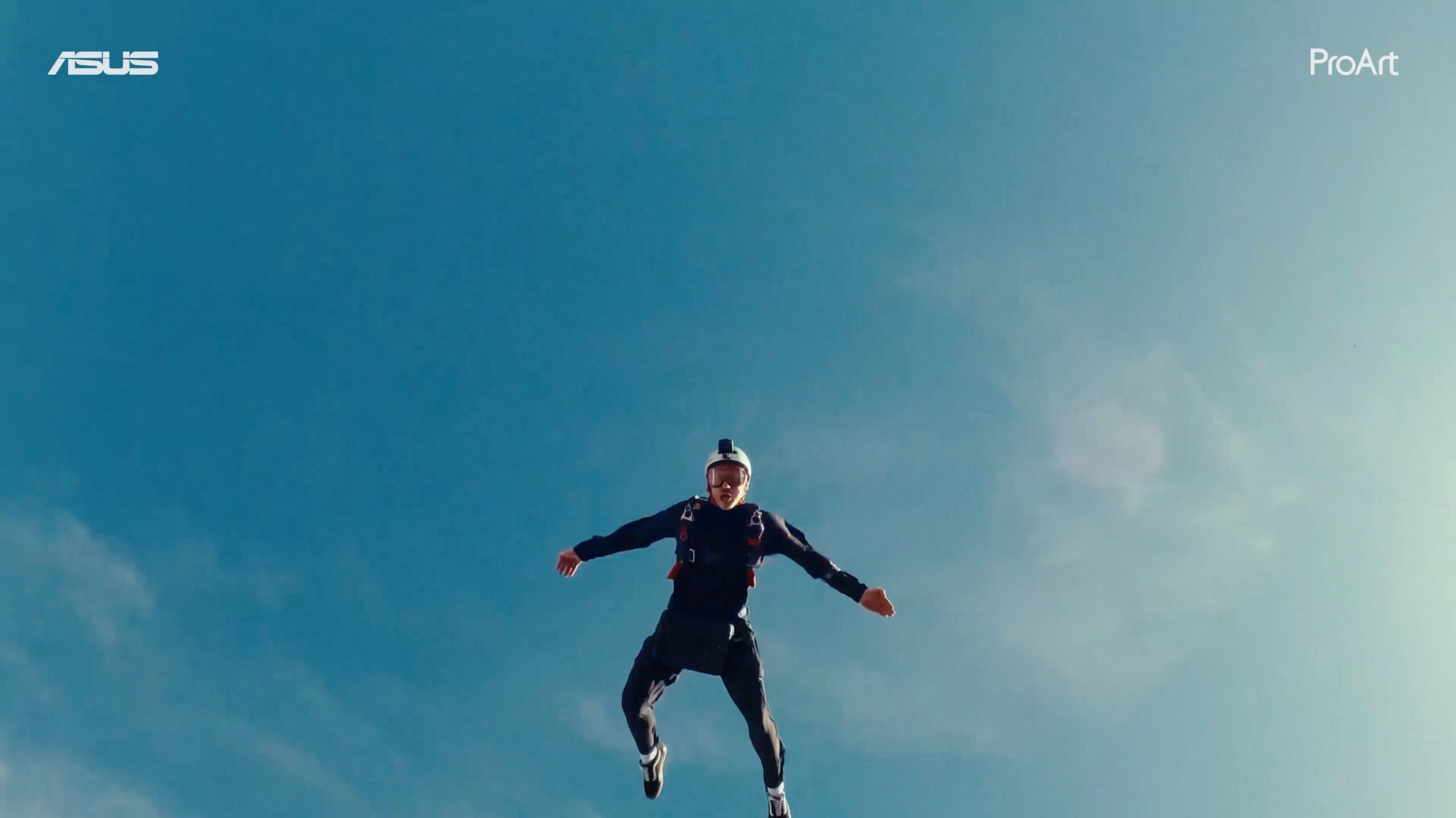Un homme vu du dessous, en chute libre, le ciel bleu derrière lui