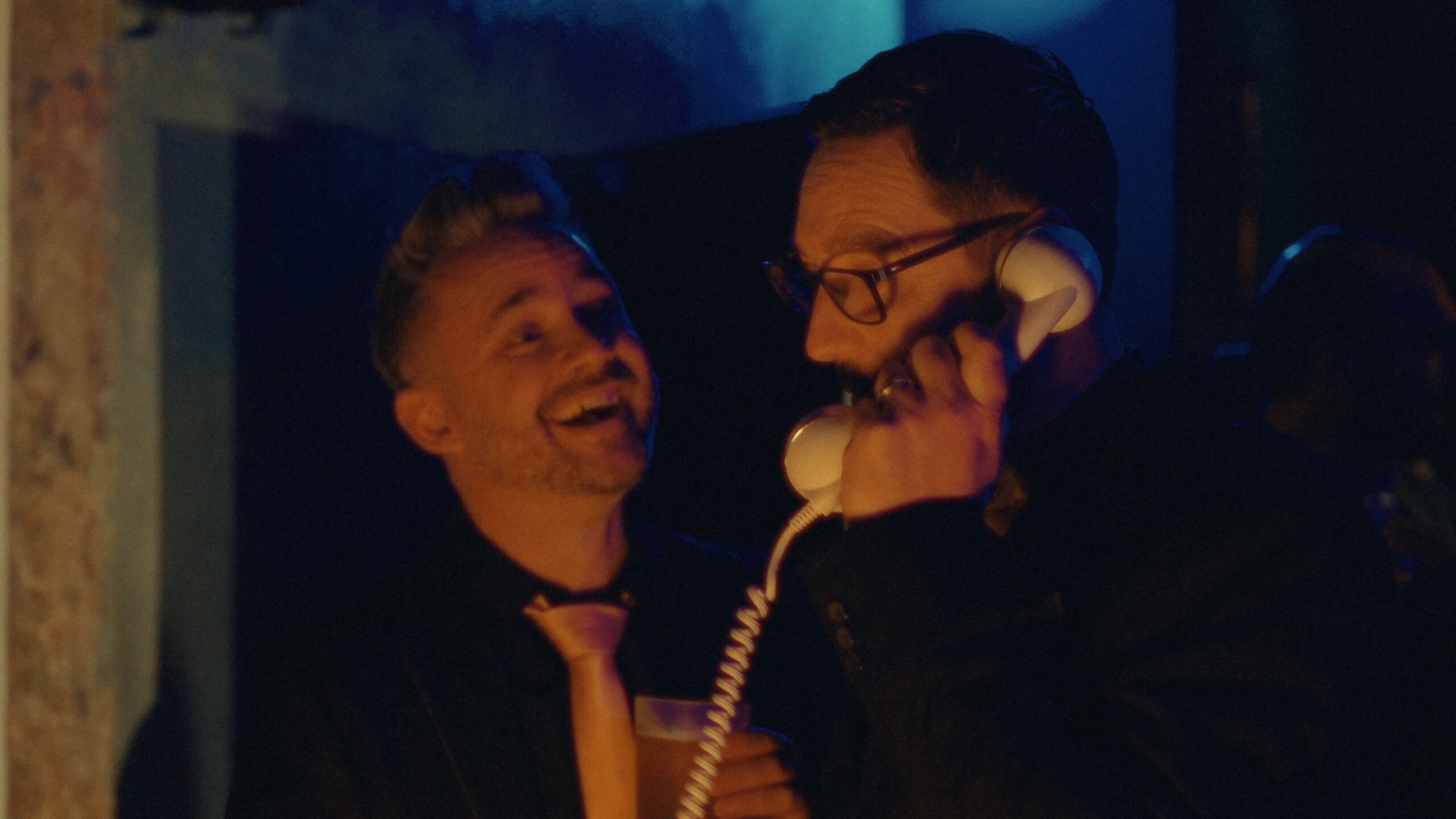 Deux participants rient en partageant un téléphone lors d'une animation de team building